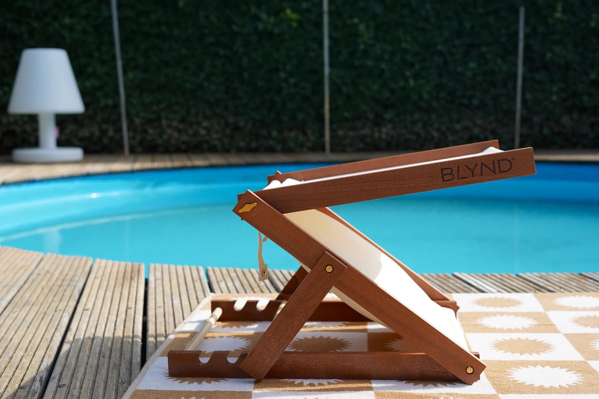 BLYND Premium Portable Beach Head Shade on towel near swimming pool wide shot within garden
