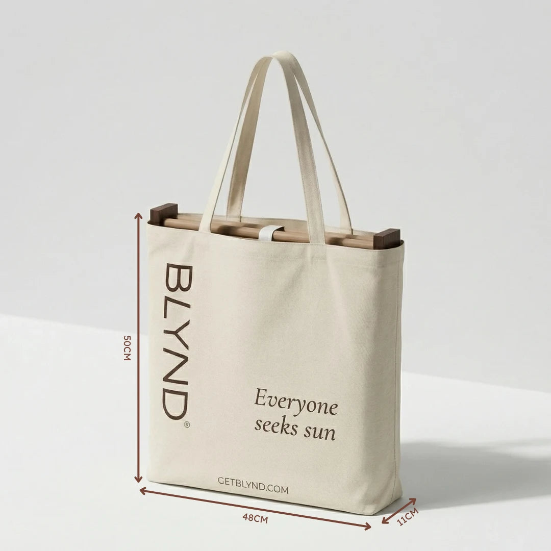 Beige tote bag with folded wooden beach head shade and bottom, featuring BLYND branding and getblynd.com website with dimensions.