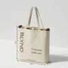 Beige tote bag with folded wooden beach head shade and bottom, featuring BLYND branding and getblynd.com website with dimensions.